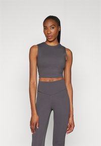 Szürke, rövidített tank top, kerek nyakkivágással, magas derekú leggings-szel kombinálva, ugyanabból az anyagból és színből, sima textúrával, minimális varratokkal.