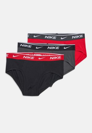 Tres calzoncillos Nike en negro, gris oscuro y rojo con cinturillas elásticas que presentan el logo de Nike y el símbolo Swoosh en colores contrastantes.