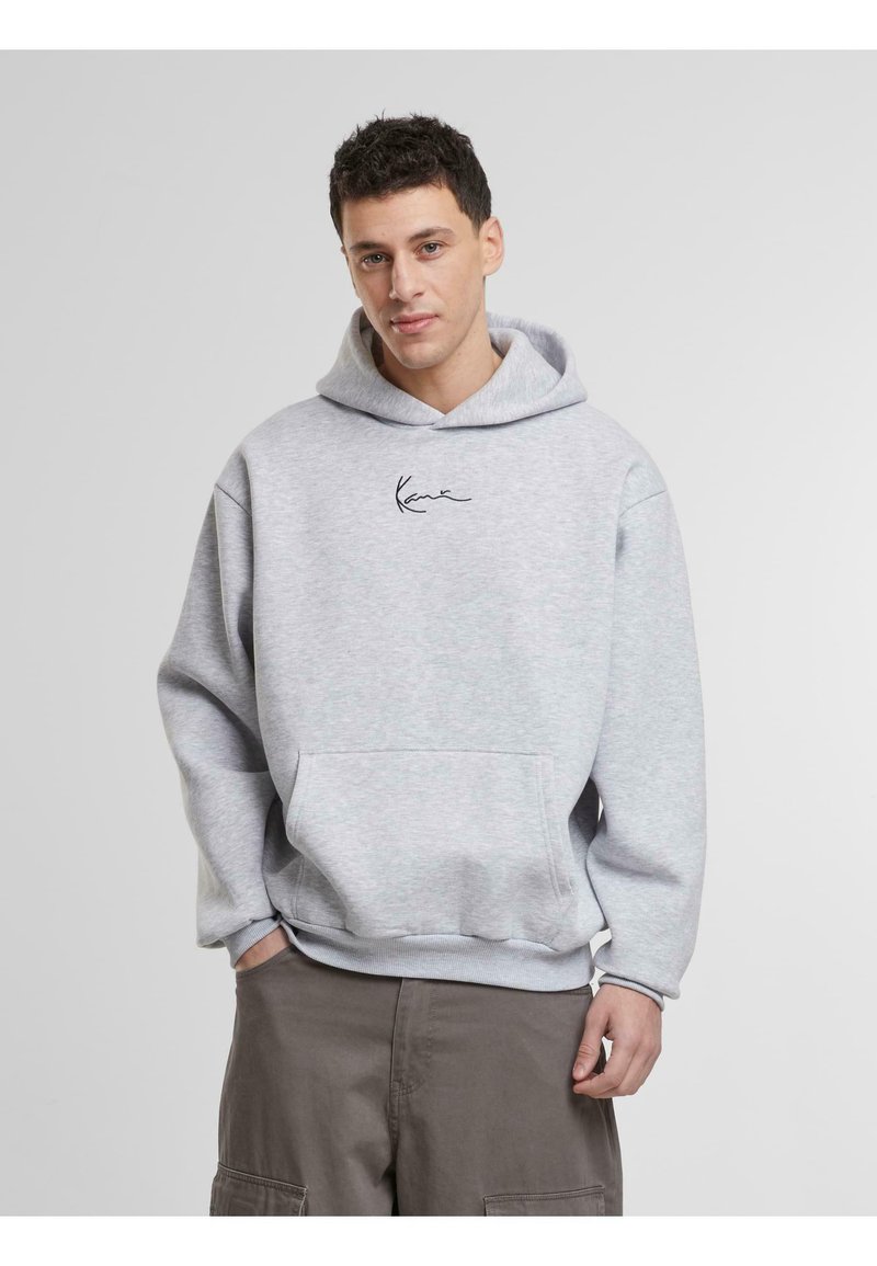 Sudadera gris con un bolsillo canguro, que presenta un logo de firma negro en el pecho, puños acanalados y una tela suave y texturizada.