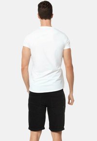 White short-sleeve t-shirt paired with black denim shorts. The shorts have rolled cuffs and two back pockets.