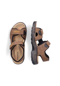 Sandales marron avec des sangles réglables, semelles noires texturées et semelles intérieures rembourrées ornées d'un motif de vagues rouges et oranges.