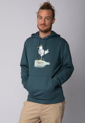 Teal katoenen hoodie met een voorzijdeafbeelding van een zeemeeuw op een fles, met gele accenten. Het ontwerp bevat een gestreept shirt en een papieren boot.