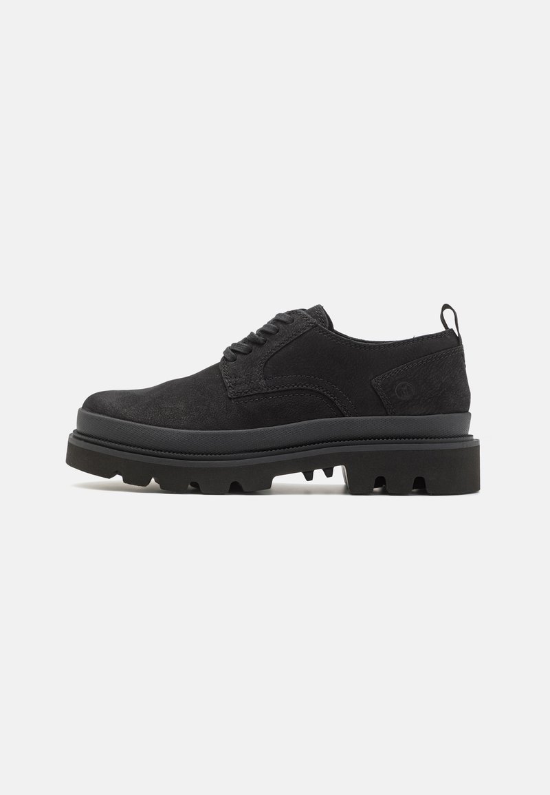 Scarpe in suede nero con una spessa suola in gomma nera, dotate di chiusura con lacci e di un linguetta sul tallone. Superficie texturizzata e design robusto.