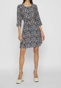 Robe à motifs floraux avec une base noire, des manches trois-quarts et une taille cintrée. La robe présente diverses couleurs, y compris le bleu et le rose.