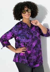 Paarse blouse met doodskop- en rozenpatronen, v-halslijn, driekwart mouwen en gestrikte manchetten, gemaakt van een lichte stof.