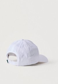 Λευκό καπέλο μπέιζμπολ με κυρτή γείσο, κατασκευασμένο από υφασμάτινο ύφασμα με υφή. Διαθέτει ρυθμιζόμενο λουρί στο πίσω μέρος και οπές αερισμού στις πλευρές.