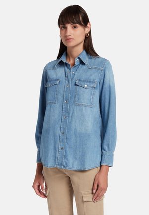 Helles blaues Denimhemd mit Knopfleiste, spitzem Kragen und zwei Brusttaschen. Mit langen Ärmeln und lockerer Passform.
