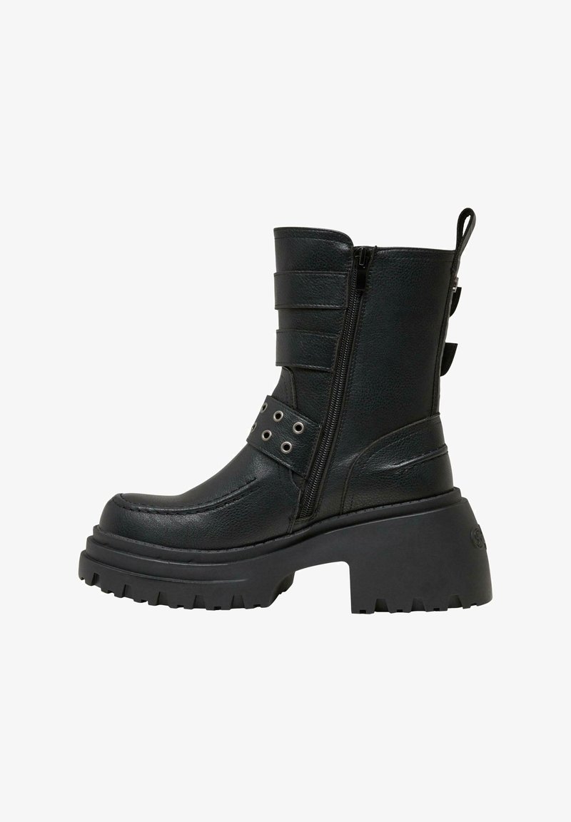 Botín de cuero negro hasta el tobillo con una plataforma gruesa, cierre lateral y correas decorativas con acentos de metal. Suela estriada para mayor tracción.