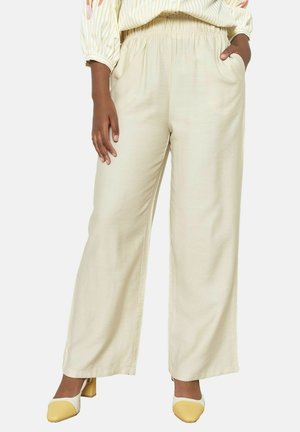 Beige wijde broek met een elastische tailleband, zijk проц beschermd info, en een zachte textuur, gecombineerd met gele blokhak schoenen.