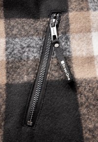 Fleecetröja med rutmönster i svart, grått och beige. Inkluderar en svart dragkedja med en dragsträng märkt "StreetOne."