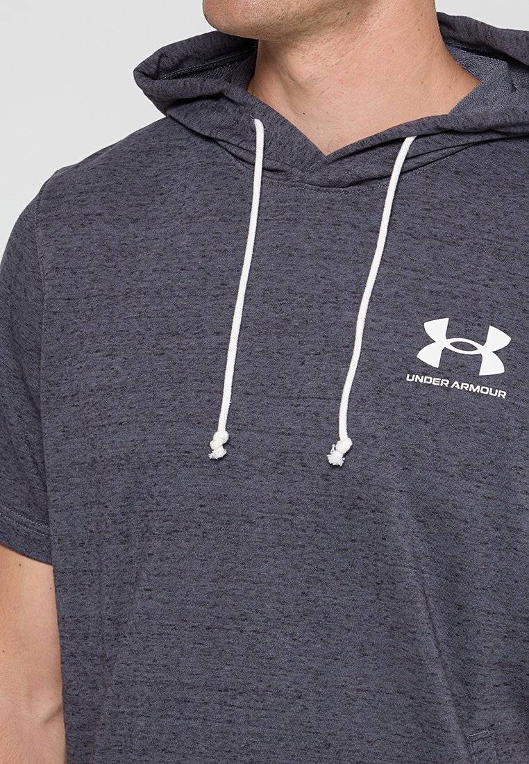 Homme portant un hoodie à manches courtes gris foncé d'Under Armour avec des cordons blancs visibles sur la poitrine.