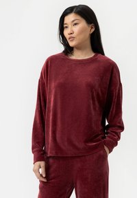 Bordeaux, fluweelachtig langemouwen top met een ronde halslijn en een losse pasvorm, gecombineerd met bijpassende broek, met een zachte textuur en subtiele glans.