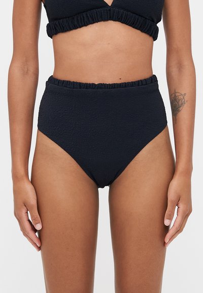 Bas de bikini noir taille haute en tissu texturé, avec une taille volanée et une finition lisse.