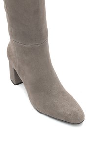 Szary zamszowy botek do kostki z szpiczastym noskiem, 7,5 cm grubym obcasem i subtelnymi detalami przeszyć. Gładka tekstura i smukły design.
