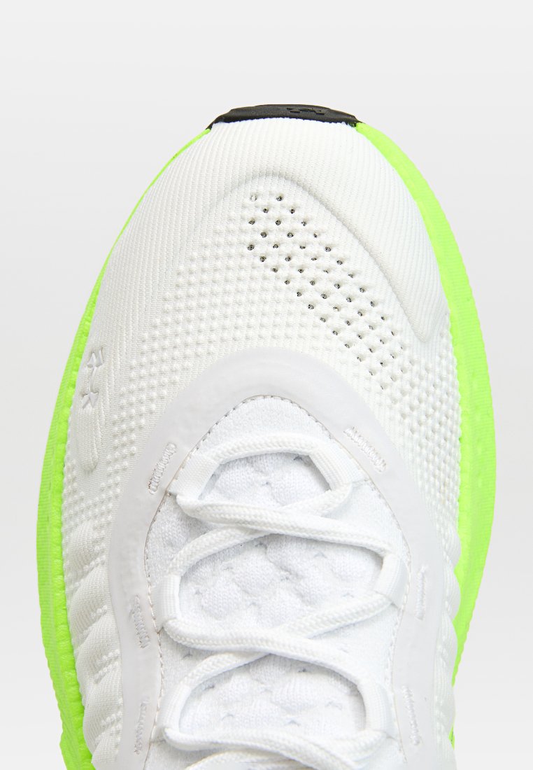 Chaussure de sport blanche avec une tige en maille texturée, semelle vert vif et accents noirs sur la languette. Présente un laçage traditionnel.