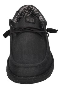 Schwarze Leinenschuhe mit runder Zehenpartie, strukturiertem Obermaterial und elastischen Schnürsenkeln. Das Innenfutter hat ein Zickzackmuster. Flexible Sohle.