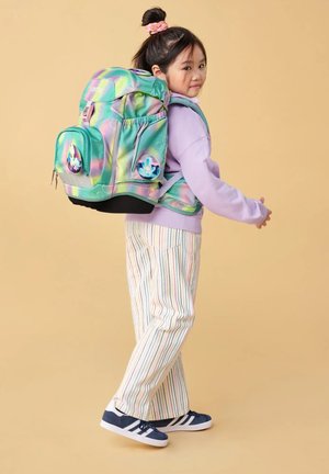 Sac à dos multicolore avec des motifs circulaires, bretelles ajustables rembourrées, deux poches latérales et une poche frontale zippée. Porté par un enfant.