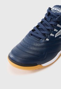 Baskets de sport bleu marine avec un dessus en cuir texturé, des détails perforés, des accents blancs et une semelle en caoutchouc naturel. Équipées de lacets plats.