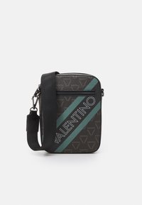 Sac bandoulière en tissu noir avec une bande diagonale teal et le logo "VALENTINO" en gras. Fermeture zippée et détail de sangle réglable.