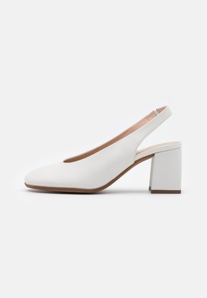 Hvide læderslingback-sko med blokhæl og rund tå, vist på en ensfarvet hvid baggrund, sidevinkel.