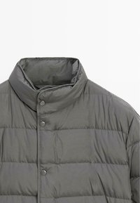 Graue gepolsterte Jacke mit hohem Kragen, horizontaler Steppung und Druckknopfverschlüssen auf der Vorderseite. Glatter, leichter Stoff.