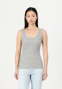 Harma, istuv tanktop, jossa on pyöreä kaula-aukko ja raidoitettu pinta, yhdistettynä vaaleansinisiin farkkuihin. Yksinkertainen, rento malli ilman logoja tai kuvioita.