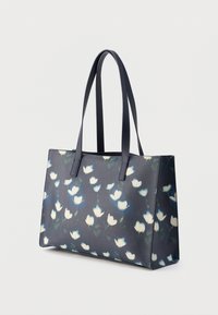 Liela auduma soma ar ziedu rakstu mīkstos zilos un baltos toņos uz tumša fona, ar divām izturīgām rokturiem un noformētu taisnstūra formu.