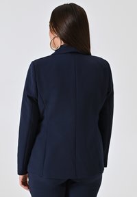 Marineblazer gemaakt van gladde stof, met een getailleerde pasvorm, notch-kraag en gestructureerde schouders, met een schone rugnaad ontwerp.