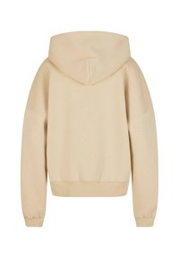 Bež majica s kapuljačom i opuštenim krojem. Ima rebraste manžete i donji rub. Glatka tekstura s jednostavnim dizajnom bez vidljivih logotipa ili uzoraka.