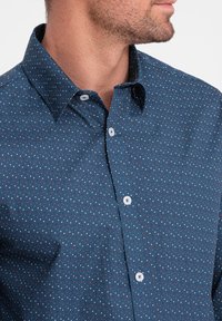 Camicia a maniche lunghe di colore navy in tessuto leggero, con un piccolo motivo a pois multicolori. Presenta un colletto a punta e chiusura con bottoni.