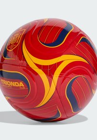 Crvena nogometna lopta s žutim i mornarsko plavim vrtložnim uzorcima, grb reprezentacije Španije i tekst "TRIONDA CLUB" na bijeloj pozadini.