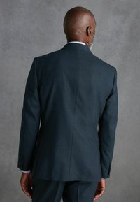 Dunkelgrau s Jacket, tailliert, glatte Textur, mit einem Schlitz hinten, weißer Kragen des Hemdes am Hals sichtbar.