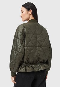 Quilted bomberjakke i olivengrøn. Har en shiny finish, ribbede manchetter og en indsnøret talje for ekstra form.