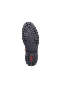 Semelle extérieure en caoutchouc noir avec des crampons profonds et des motifs hexagonaux pour l'adhérence. Présente un logo rouge au centre. Surface ferme et texturée.
