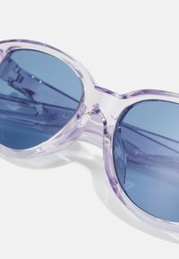 Ochelari de soare transparenti mov cu lentile albastre. Design cu ramă rotundă, având o textură netedă și detalii minimaliste în jurul lentilelor.
