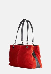 Czerwona zamszowa torba tote z czarnym, teksturowanym skórzanym dnem, podwójnymi uchwytami u góry oraz zasuwaną kieszonką z boku. Gładkie wykończenie wnętrza.
