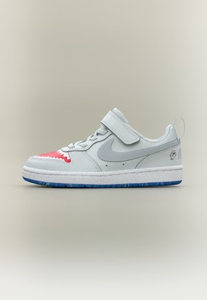 Białe niskie sneakersy z szarym logo Nike, czerwonym wzorem w kształcie rekina na czubku, niebieską podeszwą, paskiem na rzep oraz grafiką ryby na pięcie.