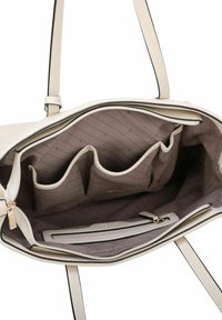 Sac cabas couleur crème avec un extérieur texturé. L'intérieur est en tissu brun clair à rayures subtiles, avec plusieurs poches et un compartiment zippé.