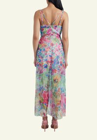 Maxi dress featuring a floral print in vibrant colors, lightweight material, thin straps, and a flowy silhouette. Worn with pink high heels.
