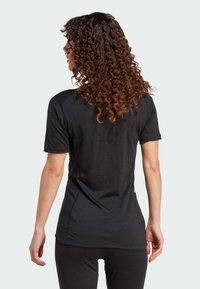 Black short-sleeve athletic shirt with a fitted design and smooth texture. Features raglan sleeves and a curved hem for comfort.