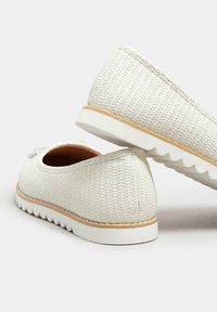 Scarpe intrecciate bianche con tomaia testurizzata, punta rotonda e rifiniture marroni a contrasto. Presentano una suola in gomma bianca con dettagli scallop.