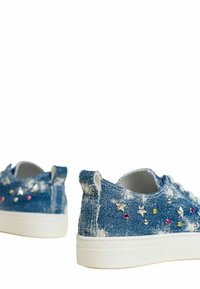 Sneakers in denim con suole bianche, impreziositi da gemme multicolori e decorazioni a forma di stella. Texture invecchiata, colore blu e design con lacci.