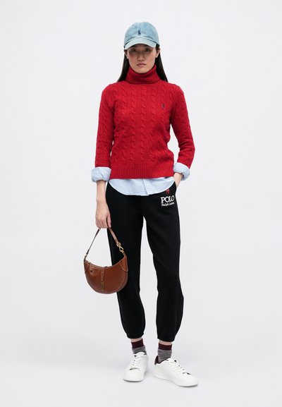 Pulover roșu tricotat, cămașă cu guler de culoare albastru deschis, pantaloni jogger negri cu logo, geantă maro, teniși albi și o șapcă de culoare albastru deschis.