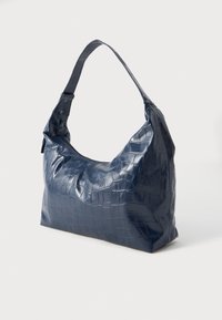 Sötétkék műbőr válltáska, fényes krokodilbőr textúrával, laza formával és egy állítható pánttal.