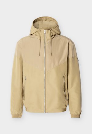 Μπεζ μπουφάν με κουκούλα, πλήρης φερμουάρ μπροστά, δύο πλαϊνές τσέπες με φερμουάρ, ελαστικά μανσέτες και σχεδιασμός με χρωματικές μπλοκ στις μανσέτες και το στήθος.