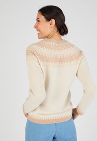 Maglione con motivo crema e beige, collo rotondo, texture a maglia e finitura morbida. Presenta un design geometrico sul giromanica e sui polsini.