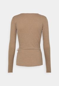 Beige ribbed pitkähihaine paita, jossa on tiukka vyötärö ja ohut sivunutka, esitetty takaa yksinkertaisella taustalla.