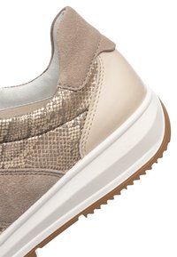 Béžová pata tenisky s semišovými a kovovými panely s hadím vzorem, bílá střední podešev a hnědá gumová podrážka se zdrsněným vzorkem.