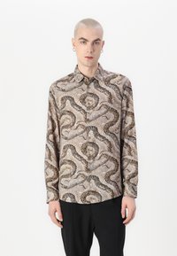 Beige színű, hosszú ujjú ing, melynek barna és fekete kígyómintázata van, standard gallérral és lekerekített szegéllyel.
