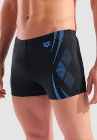 Schwarze Badehosen mit blauen diagonalen Streifen und einem kleinen grauen Logo. Hergestellt aus elastischem Material, das für Komfort und Leistung ausgelegt ist.